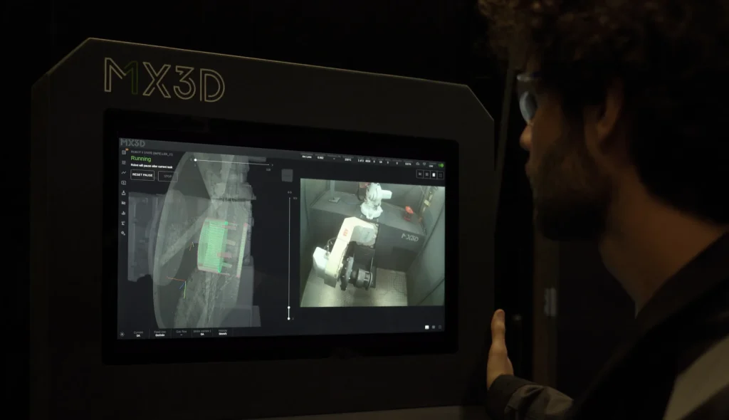 A guy monitoring the 3D printing process of MX3D with M1 and MX Metal AM Systems and MetalXL WAAM software.
